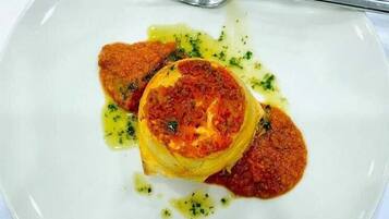 Un plato de comida con un tenedor sobre un plato blanco, con la etiqueta 'Excelsior HOTEL & RESIDENCE'.