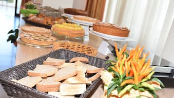 Ein reichhaltiges Buffet mit verschiedenen Backwaren und einer dekorativen Anordnung aus Karotten und Ananas.