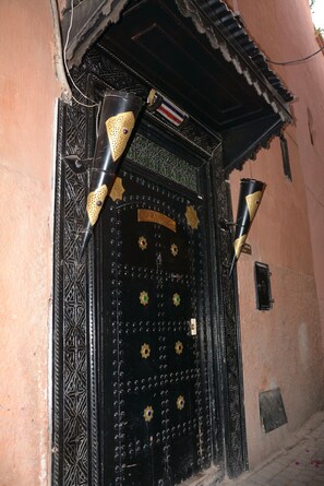 A black ornate door with decorative elements and a metal plaque. - Riad Assalam (Marrakech)