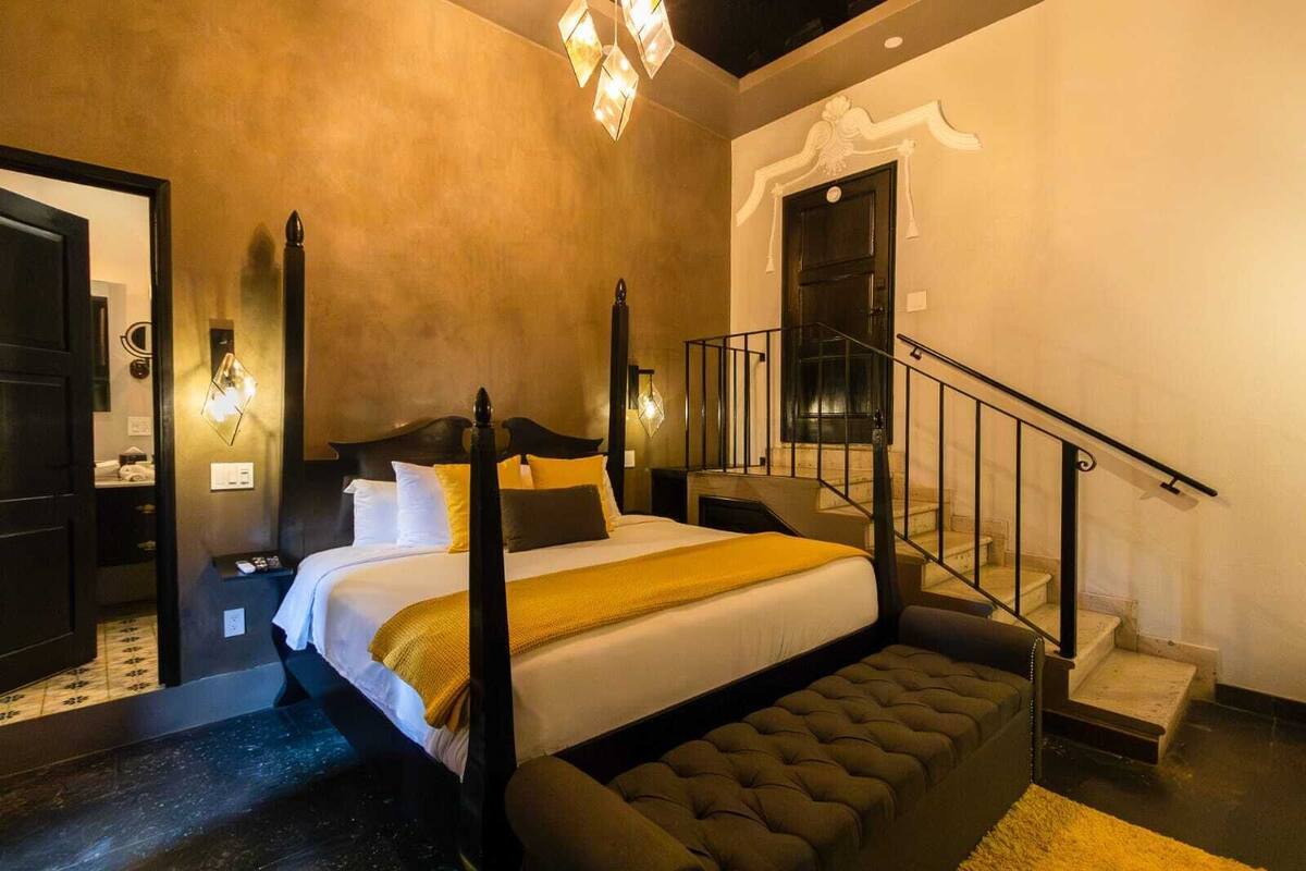 Une chambre à coucher avec un lit à baldaquin, un escalier et un grand miroir.