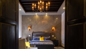 A bedroom with a large bed, a chandelier, and a nightstand. - Villa Limon Hotel Boutique (San Miguel de Allende)