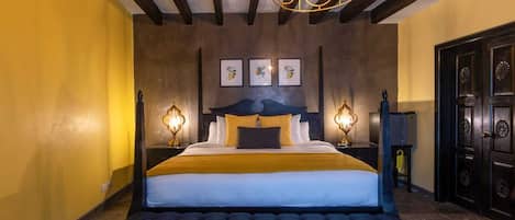 Una cama grande con cabecera capitonada, dos lámparas de noche y un candelabro.