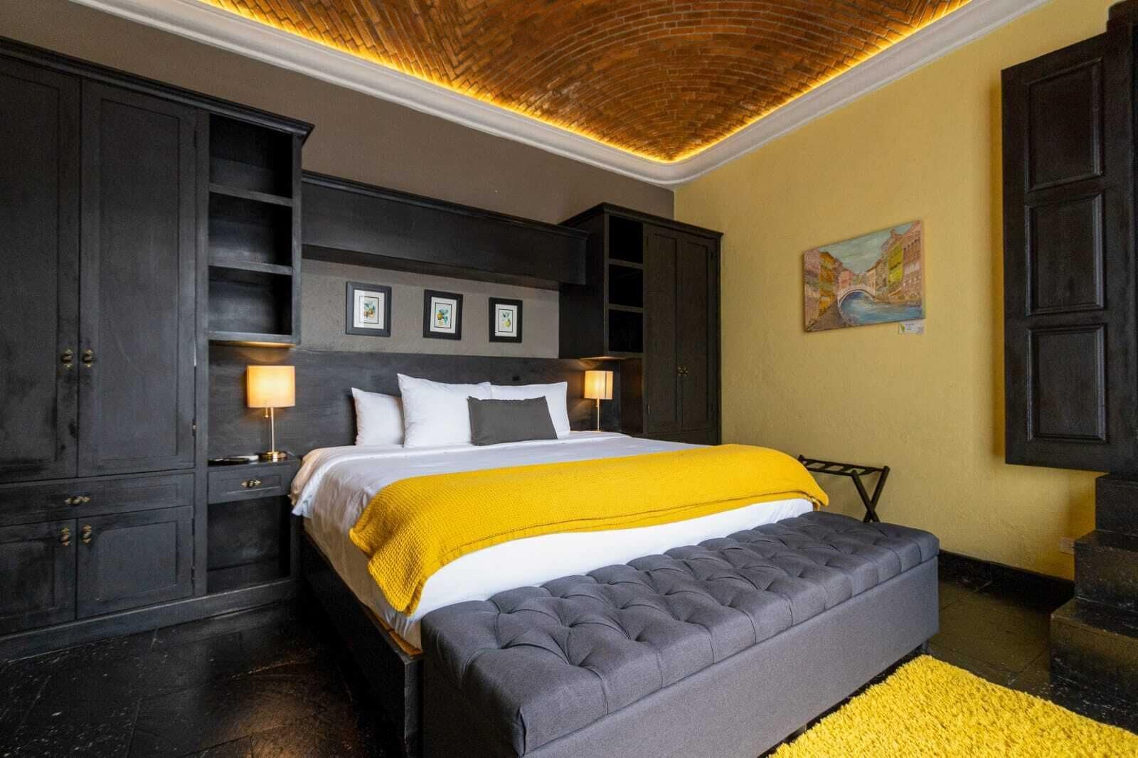 Un dormitorio con una cama grande, un armario de madera oscura y una pared de acento amarilla.