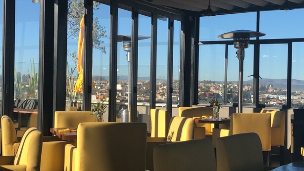 A restaurant with large windows offering a view of a cityscape. - Villa Limon Hotel Boutique (San Miguel de Allende)