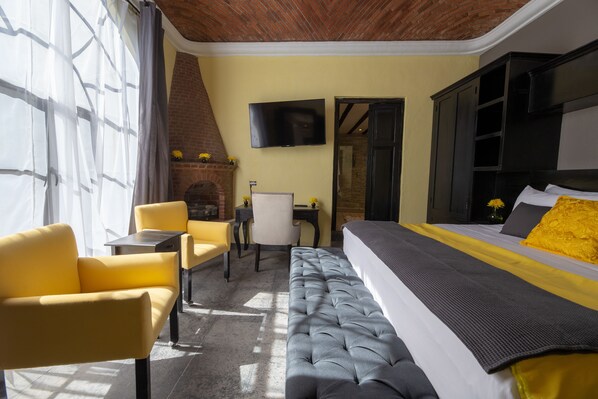 Ein Hotelzimmer mit Bett, einer Sitzecke, einem Sessel, einem Schreibtisch und einem Fernseher.