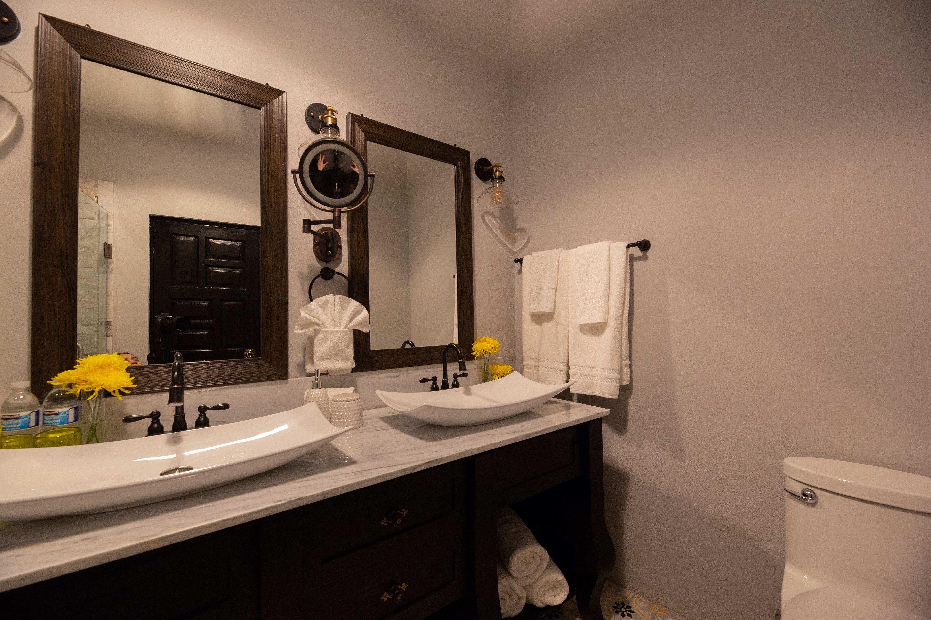 Ein Badezimmer mit Waschbecken, Spiegel, Handtuchhalter und Toilette.