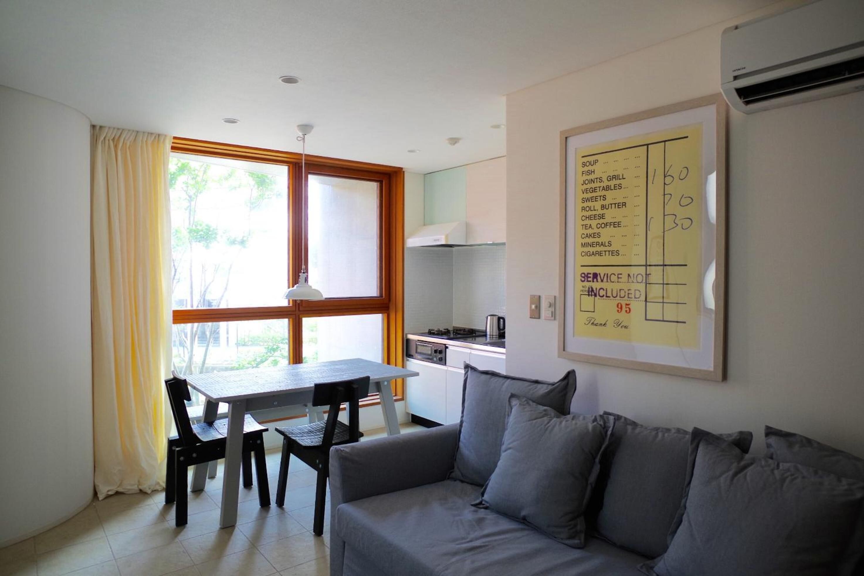 A compact living space with a dining area, kitchenette, and a sofa.