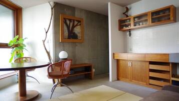 Ein moderner Essbereich mit einem runden Tisch, Stühlen und einer Pflanze. An der Wand hängt ein Gemälde und über der Arbeitsplatte befinden sich Holzschränke.