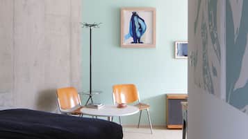 A bedroom with a bed, two chairs, a desk, and a floor lamp.