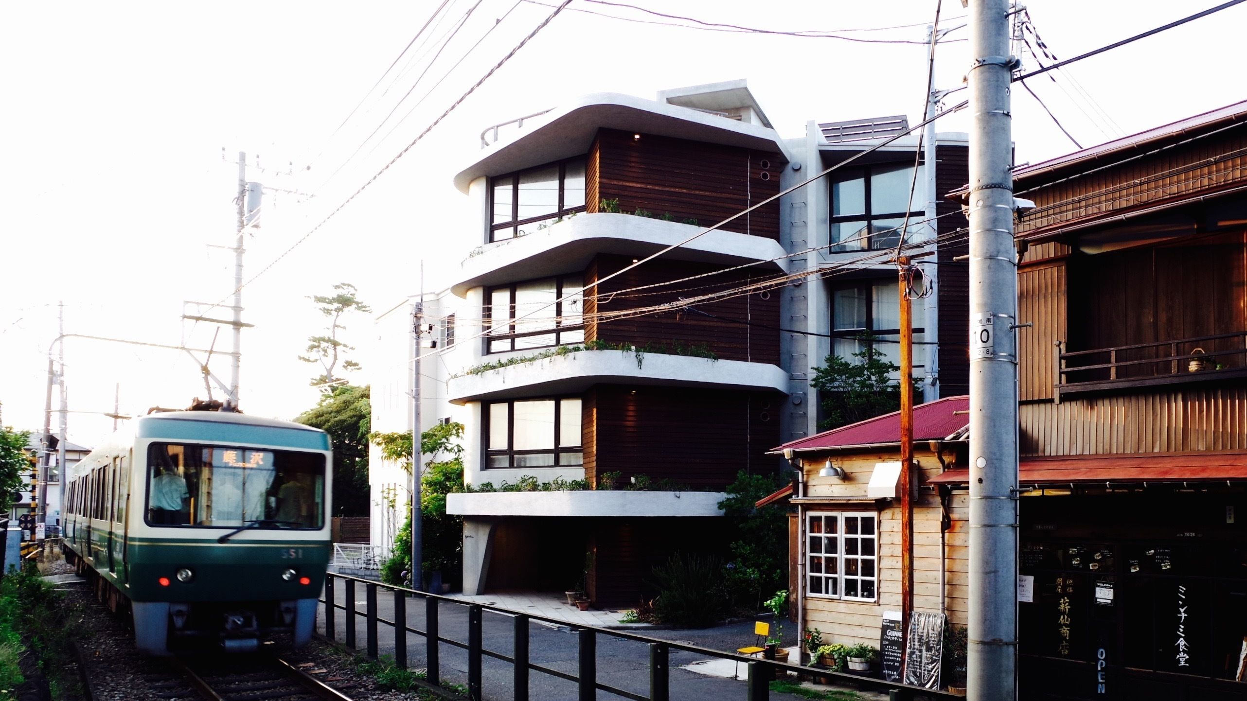 A modern building with multiple balconies and a small shop at the ground level.