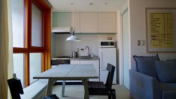 A compact kitchen with a dining table, chairs, a microwave, and a refrigerator.
