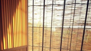 A tatami mat room with a shoji screen, a black mat, and a small table with a cup and a container. - Sango Katase Guest Rooms (Fujisawa)