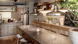 A modern kitchen with wooden cabinets, a granite countertop, hanging pendant lights, and bar stools. - Sango Katase Guest Rooms (Fujisawa)