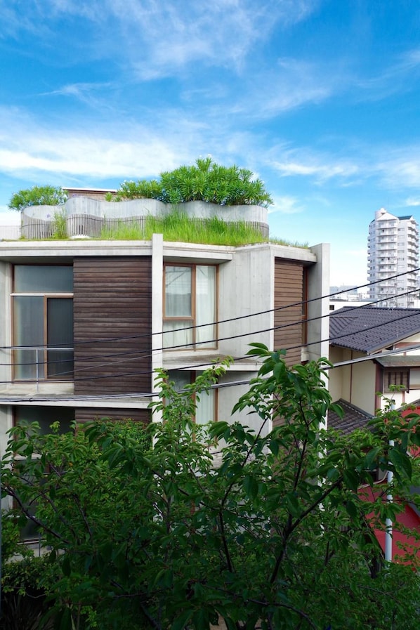 A modern two-story building with a flat roof, large windows, and a visible balcony. - Sango Katase Guest Rooms (Fujisawa)