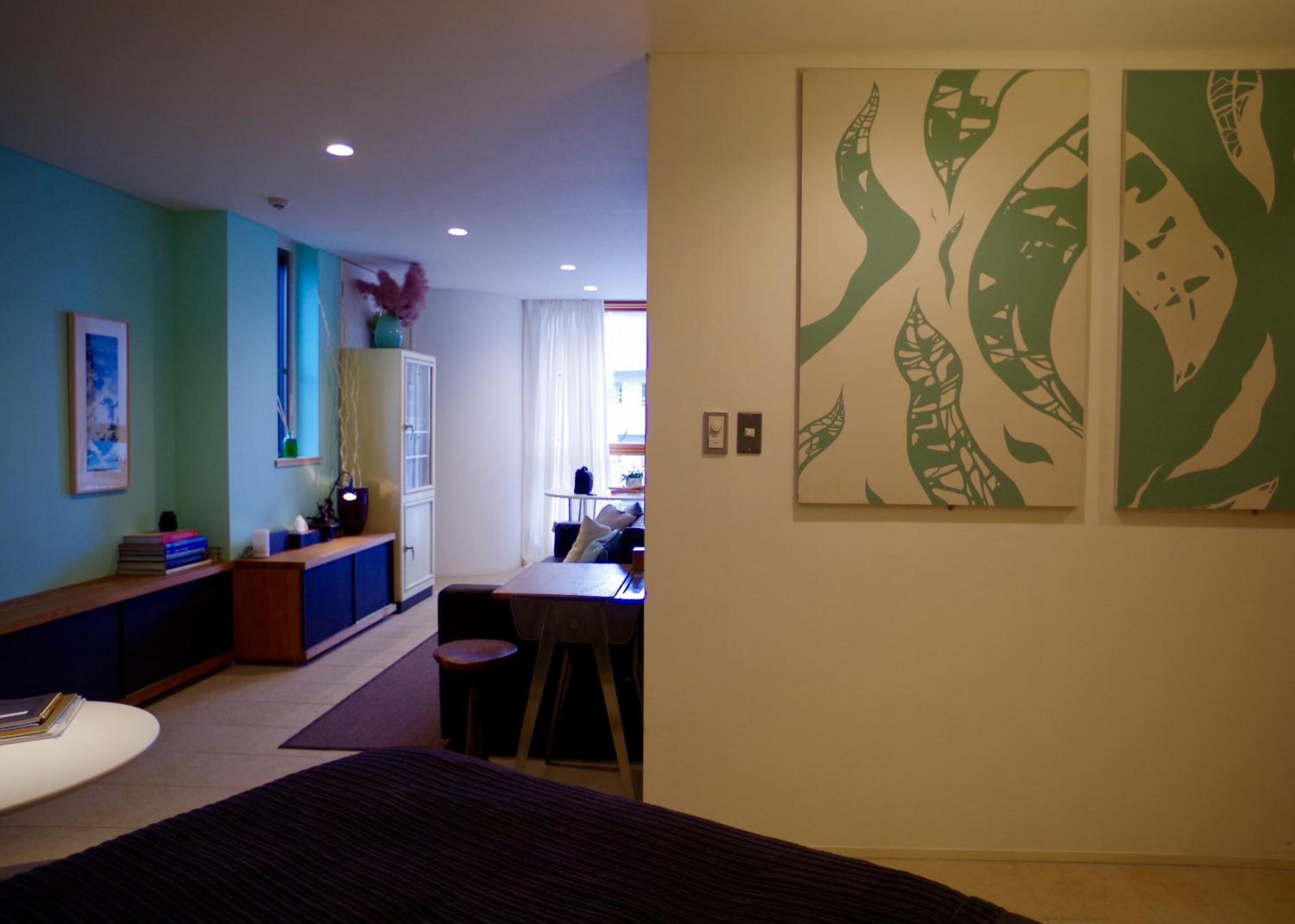 Ein Hotelzimmer mit einem Bett, einem Schreibtisch und einem Stuhl. Zwei Gemälde hängen an der Wand.