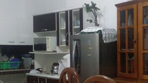 Una cocina con microondas, refrigerador, armarios de madera y una mesa de comedor con sillas.