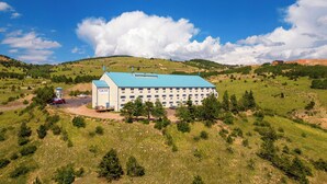 A large building with a blue roof, surrounded by green hills and trees. - Gold King Mountain Inn (Cripple Creek)