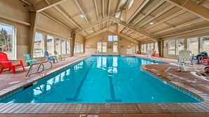 An indoor swimming pool with clear glass walls, a high ceiling, and a tiled floor. - Gold King Mountain Inn (Cripple Creek)