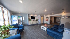 A spacious living area with blue sofas, a coffee table, and a refrigerator. There is a kitchen area with cabinets and a sink. - Gold King Mountain Inn (Cripple Creek)