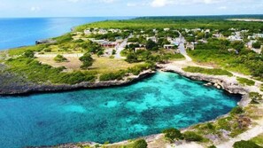 A coastal village with houses along a narrow waterway, surrounded by lush greenery and clear blue waters. - Guesthouse Villa la Isla (La Romana)