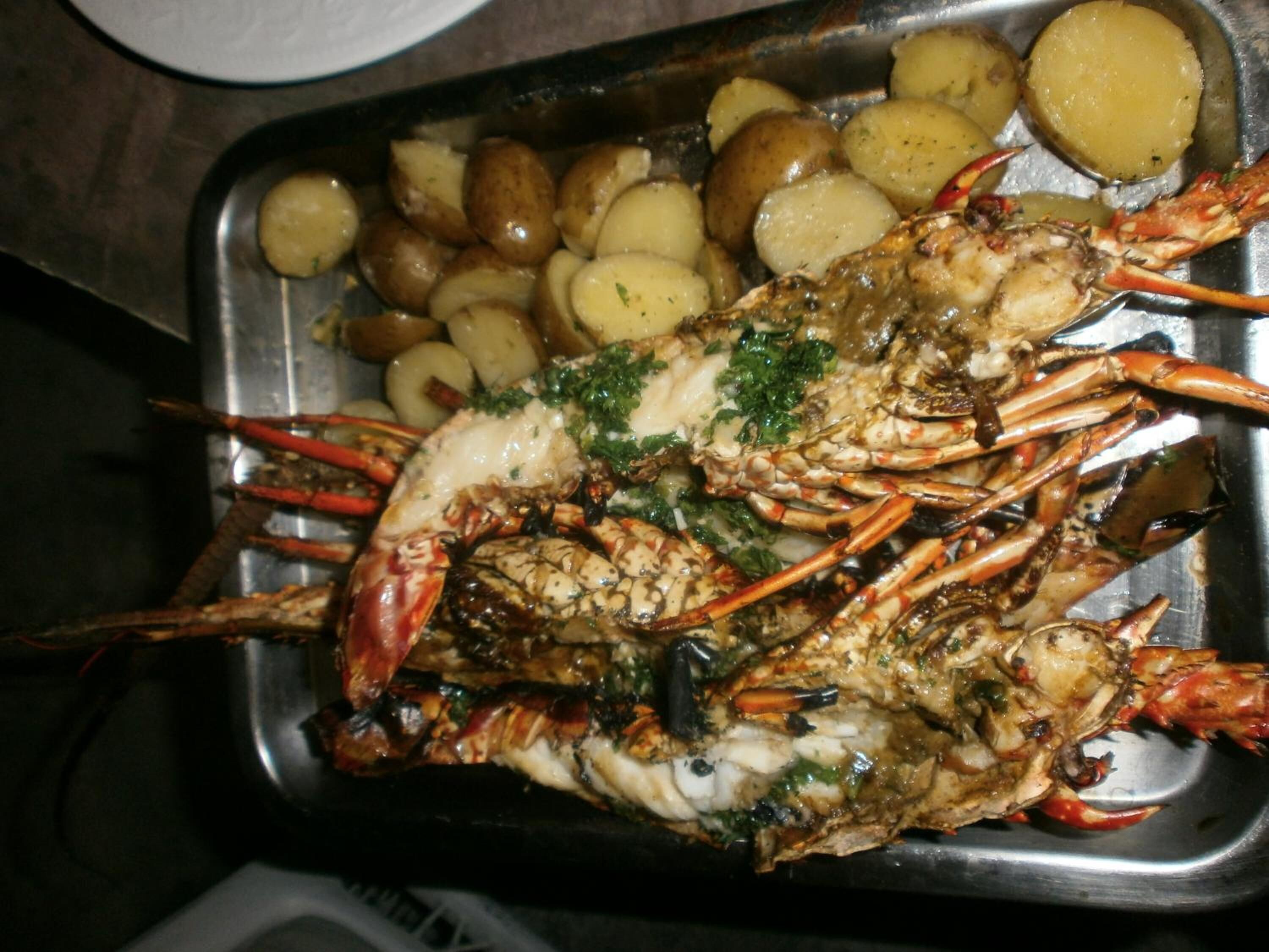 A tray with a cooked lobster and potatoes.