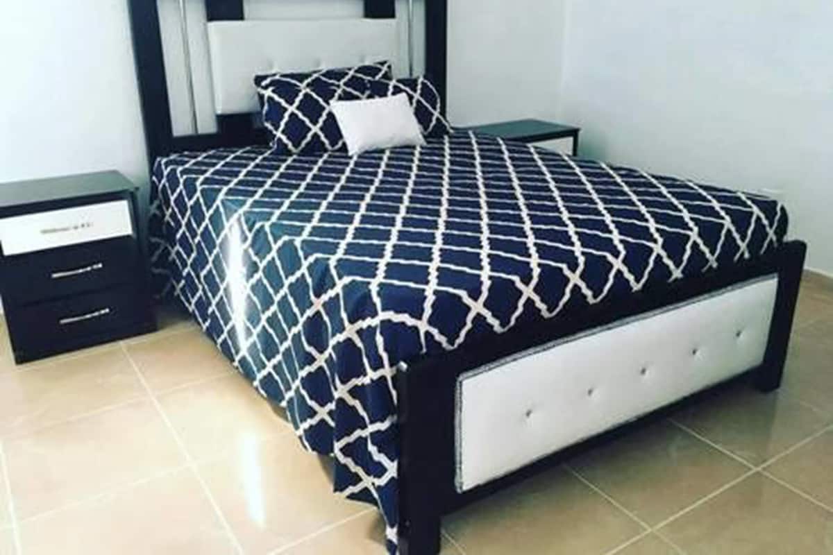 A neatly arranged bedroom with a bed, two nightstands, and a drawer unit.