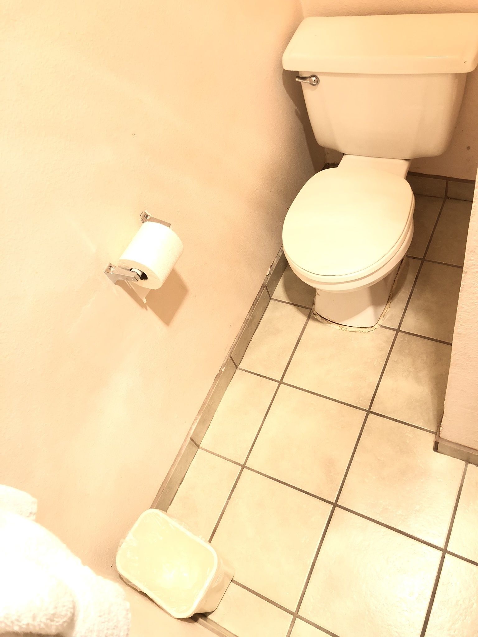 A bathroom with a toilet, a toilet paper holder, and a small trash bin.