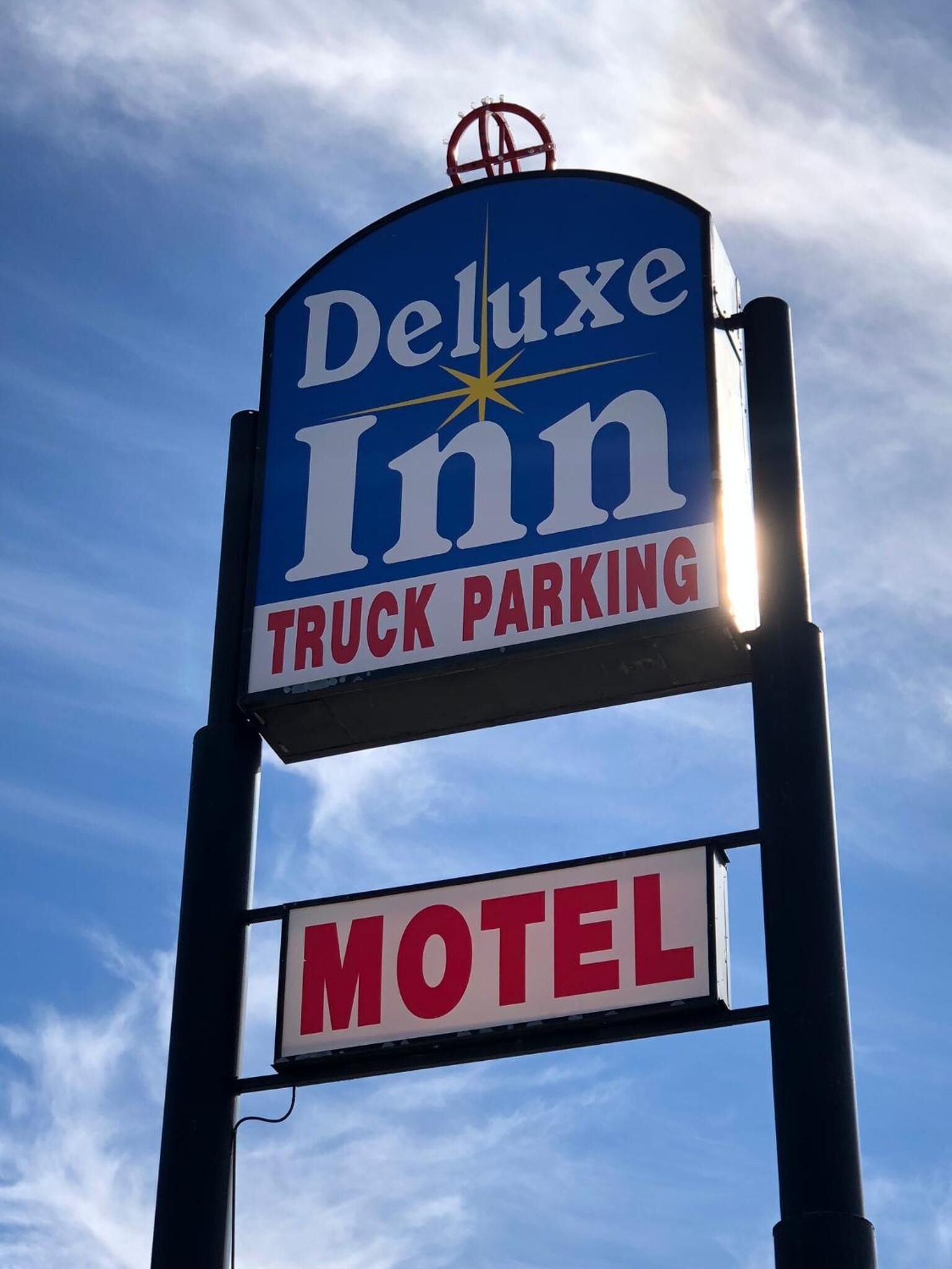 A sign for a Deluxe Inn Motel with a truck parking sign below it.