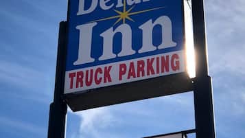 A sign for a Deluxe Inn Motel with a truck parking sign below it.