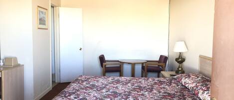 Een hotelkamer met een bed, een bureau, een stoel, een tafeltje en een lamp.