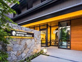 Η εξωτερική όψη του ξενοδοχείου Shizuotetsu Hotel Prezio, με τον πέτρινο τοίχο, την γυάλινη είσοδο και τον μοντέρνο σχεδιασμό του.