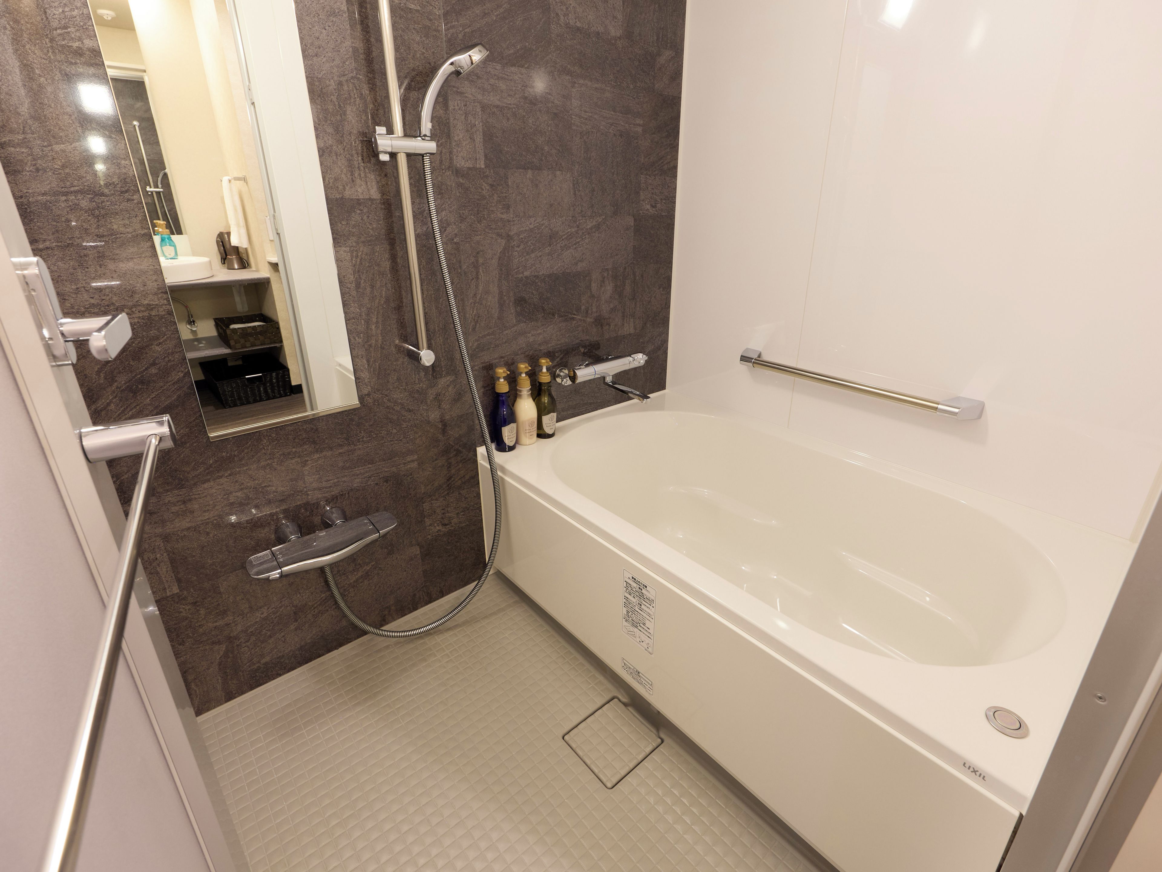A modern bathroom with a bathtub, shower, and handrails.