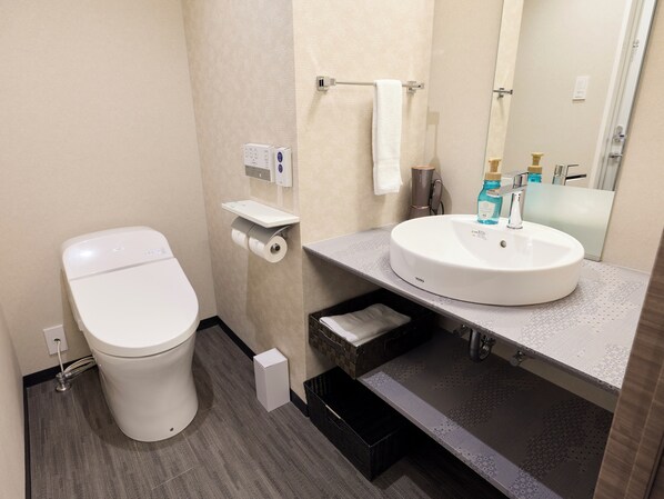 Un baño moderno con inodoro, toallero, lavabo y espejo.