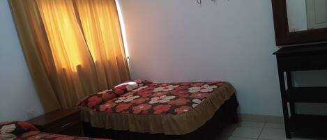 Un dormitorio con dos camas, un aparador de madera, un espejo y una estantería en la pared.