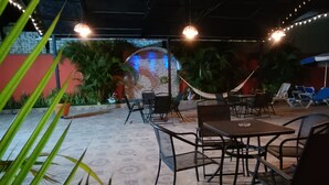 An outdoor seating area with tables and chairs, surrounded by potted plants and a hammock. - Hotel Lulu (Tondoroque)