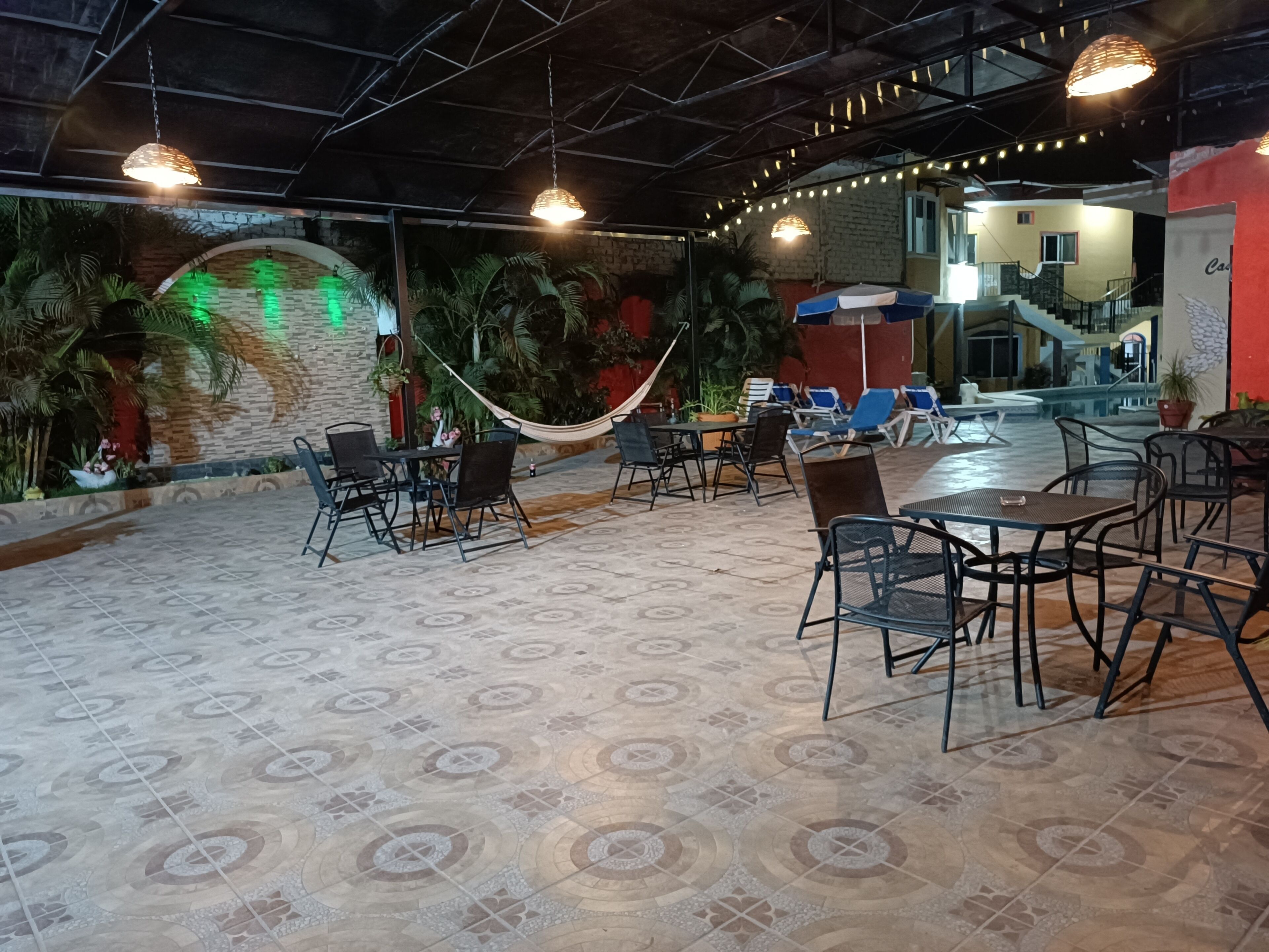 An indoor patio area with tiled flooring, outdoor seating, and hanging lights.
