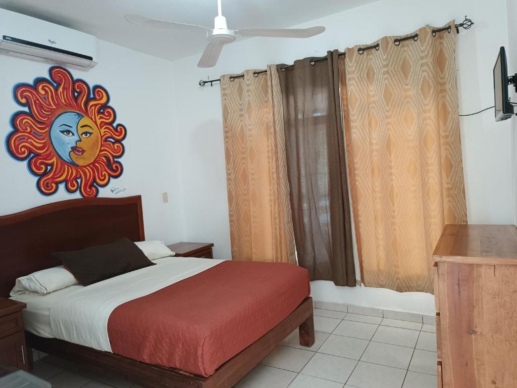 Un dormitorio con una cama, una mesita de noche, un aparador de madera, un ventilador de techo y un televisor montado en la pared.