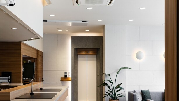 A modern hotel lobby with a reception desk, a seating area with a sofa and armchairs, a potted plant, and an elevator. - Fujieda Park in Hotel (Fujieda)