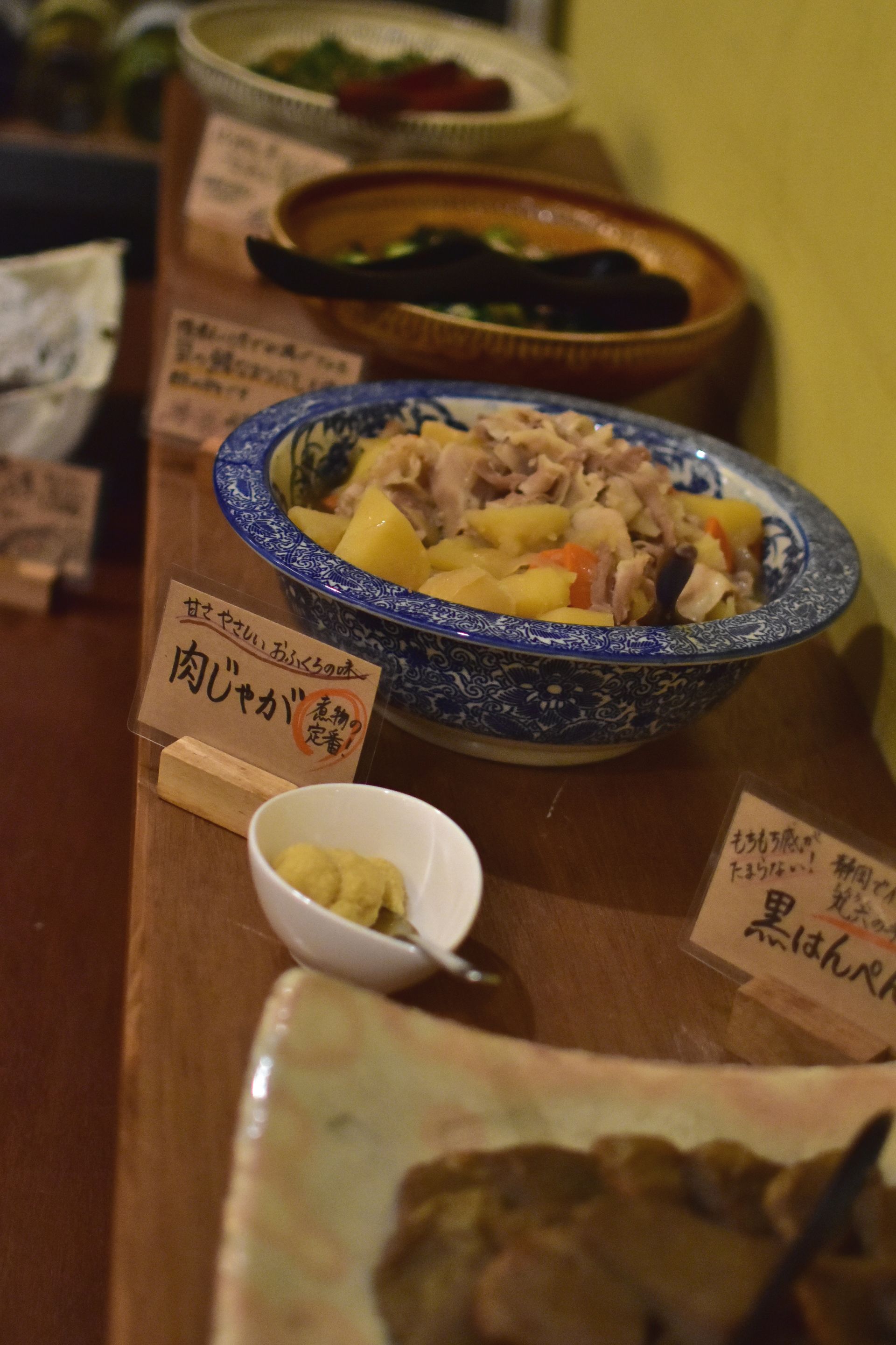 A table with various dishes, including a bowl of meat and vegetables, and several small bowls with condiments.