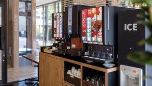A vending machine area with Coca-Cola and ICE branded machines, a wooden counter, and a window with blinds. - Fujieda Park in Hotel (Fujieda)