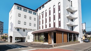 A modern hotel with a white facade, multiple floors, and a covered entrance area. - Fujieda Park in Hotel (Fujieda)