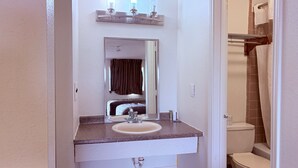 Une salle de bain avec un lavabo, un miroir et des toilettes.