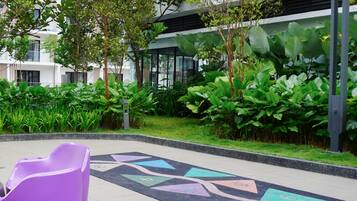A modern outdoor area with a purple seating area, lush greenery, and a patterned floor.