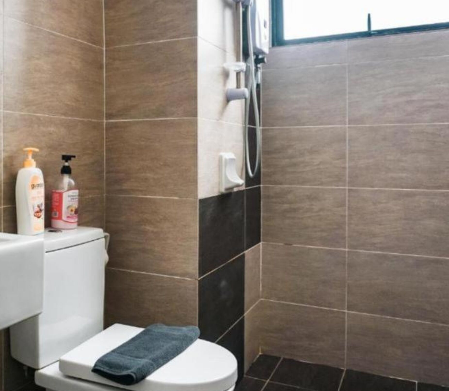 A bathroom with a toilet, a towel, and two bottles of toiletries.