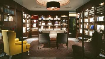 A library with bookshelves, a sofa, and a yellow armchair.