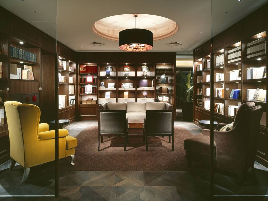 A library with bookshelves, a sofa, and a yellow armchair.