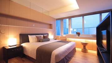 A modern bedroom with a large bed, bedside tables, a TV, and a window with a view.