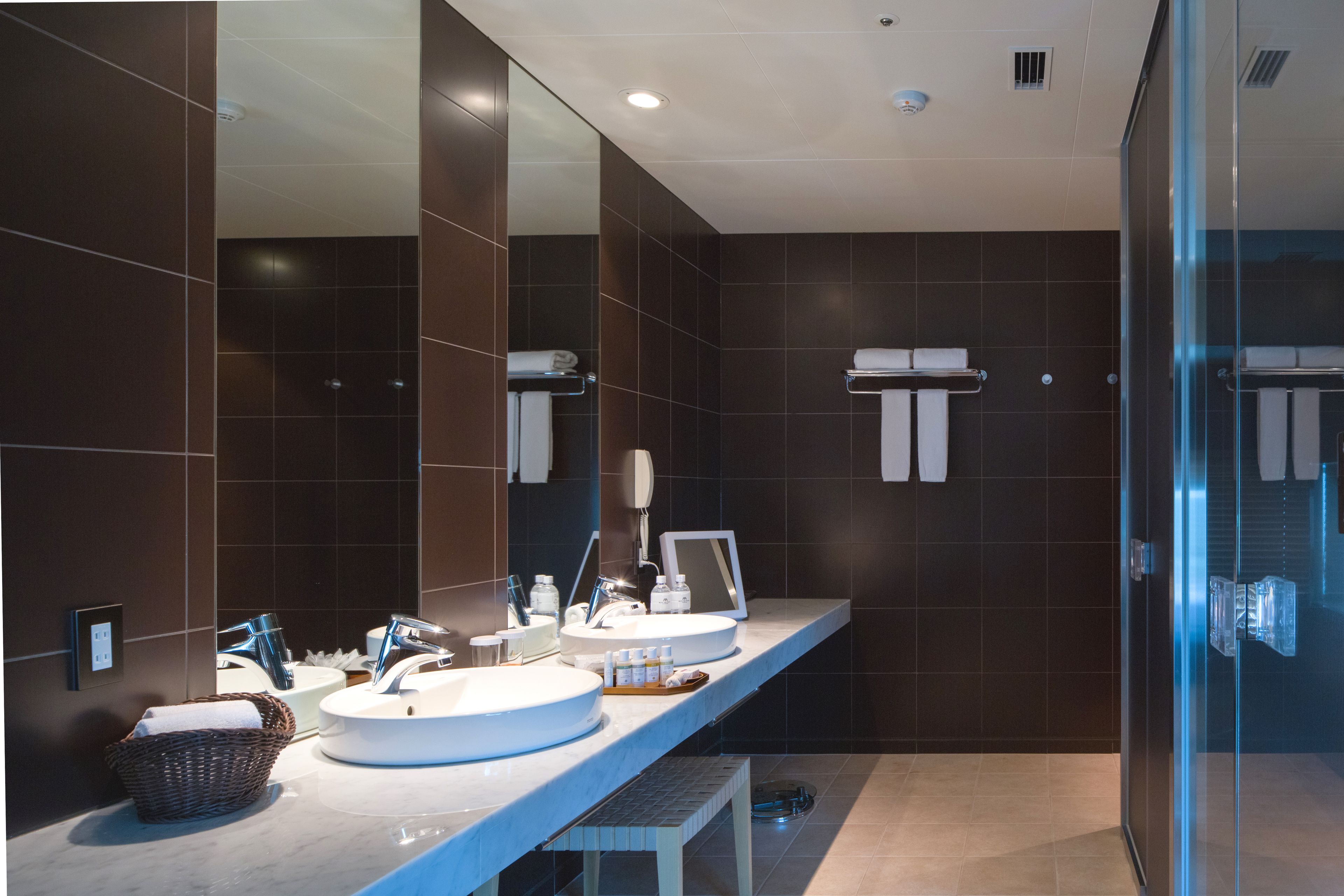 A modern bathroom with two sinks, a large mirror, and a glass shower enclosure.
