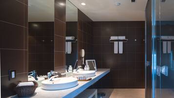 A modern bathroom with two sinks, a large mirror, and a glass shower enclosure.