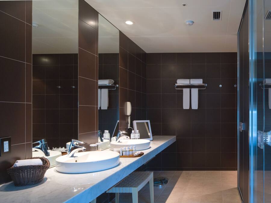 A modern bathroom with two sinks, a large mirror, and a glass shower enclosure.